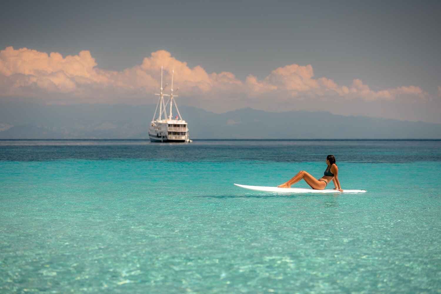 Stand-up paddleboarding in crystal clear waters with luxury liveaboard boat in Indonesia