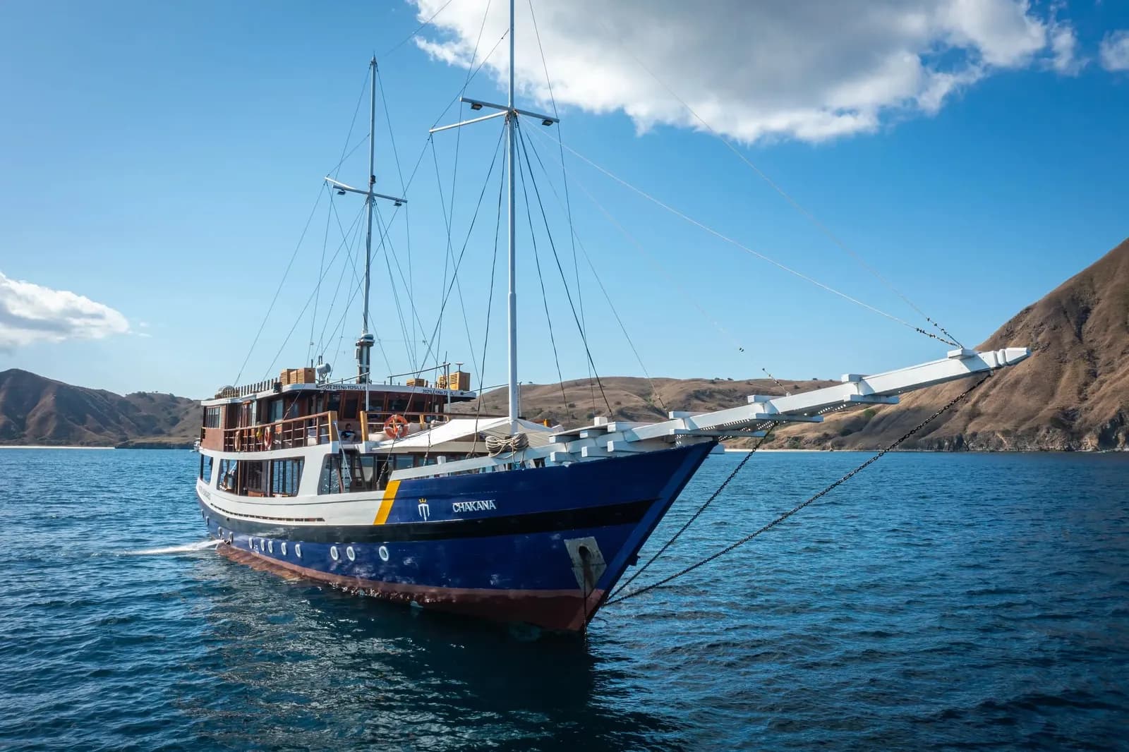 Indo Master liveaboard – vessel underway with twin masts and wooden hull – Indonesia.